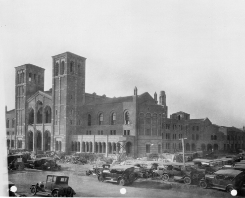 A black and white photograph of cars from the 1920s and building materials surrounding Royce Hall.