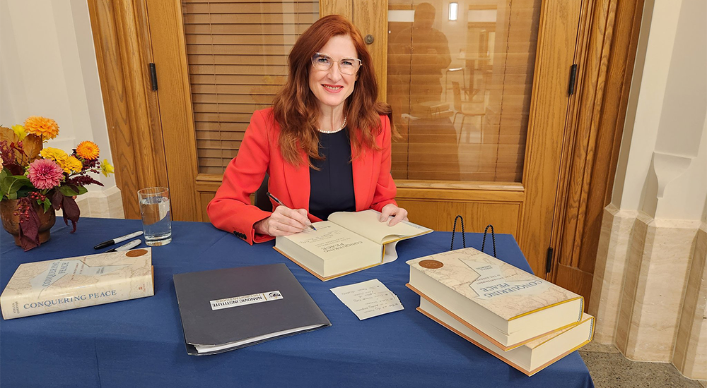 Stella Ghervas signing books at a table. 