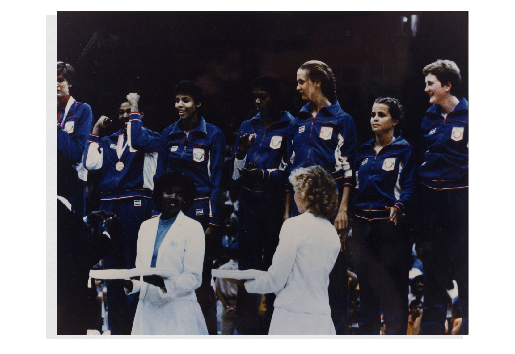 Members of the U.S. women’s national basketball team who won the gold medal in the 1984 Olympics standing on a podium at an award ceremony. Denise Curry, a graduate of the UCLA College and a former Bruin basketball player, is pictured (far right) looking as medals are being handed out.