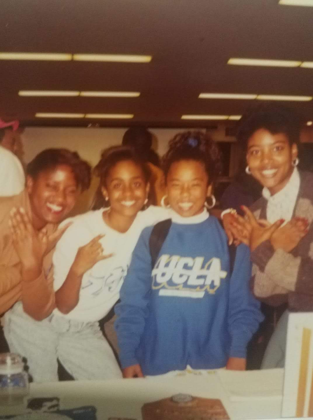 A photograph of Thuy Cooper with three of her classmates in an indoor setting.