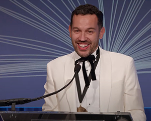 Justin Torres at a podium in a white jacket giving speech at National Book Awards ceremony