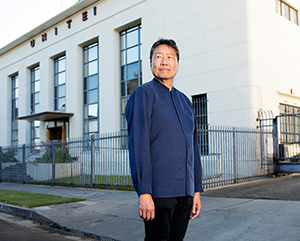 Kent Wong standing in street in front of building with "UNITE!" on the exterior