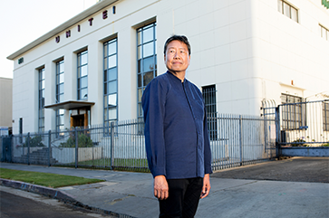 Kent Wong standing in street in front of building with "UNITE!" on the exterior