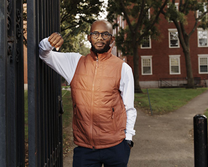 Eddie Cole in white shirt and orange vest leaning against gate.