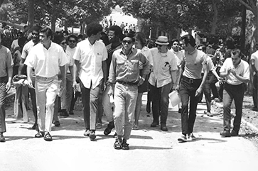 Black-and-white photo of Morgan Chu (front) marching with other students at UCLA in the 1960s