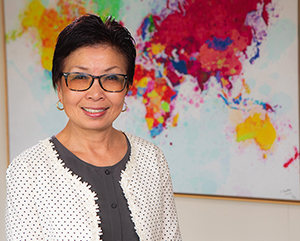 Cindy Fan in front of colorful world map painting