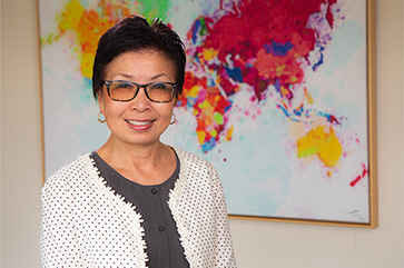 Cindy Fan in front of colorful world map painting