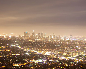 Los Angeles skyline sits below clouds and skyglow at night