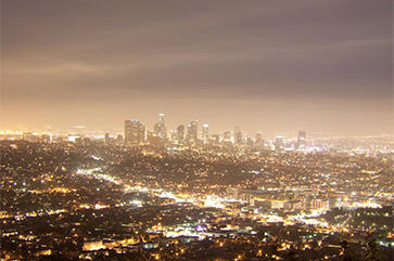 Los Angeles skyline sits below clouds and skyglow at night