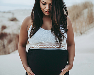 Pregnant woman looking down and holding her belly