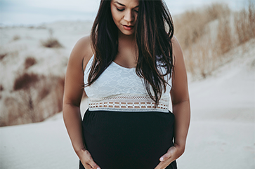 Pregnant woman looking down and holding her belly