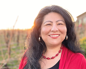 Head-and-shoulders photo of Claudia Salcedo with red necklace and top