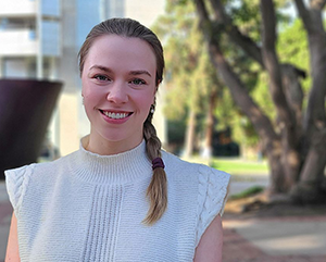 Portrait of Ekaterina (Katya) Khlystova in a white blouse standing outside on a sunny day.