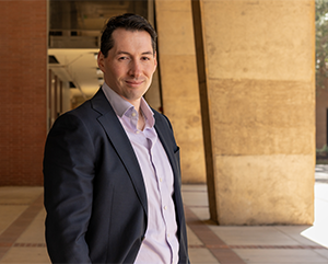 Chris Tausanovitch standing in a stone courtyard on a sunny day.