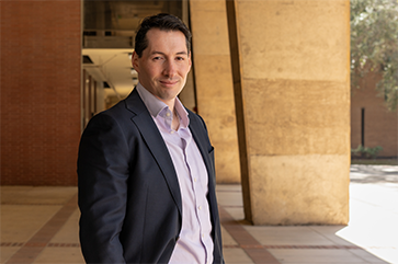 Chris Tausanovitch standing in a stone courtyard on a sunny day.