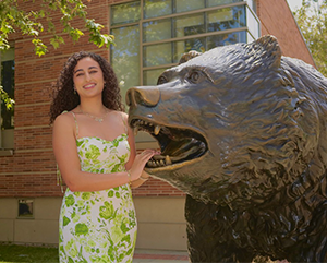 Catarina+Gerges+363-241 Catarina Gerges in a white dress with green flowers standing next to the Bruin statue.