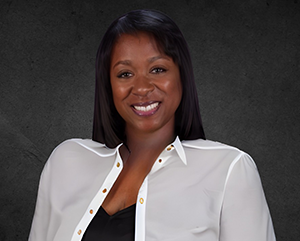 brooks-sonya-363-241 Sonya Brooks in a white blouse, smiling, against a dark graphite background.