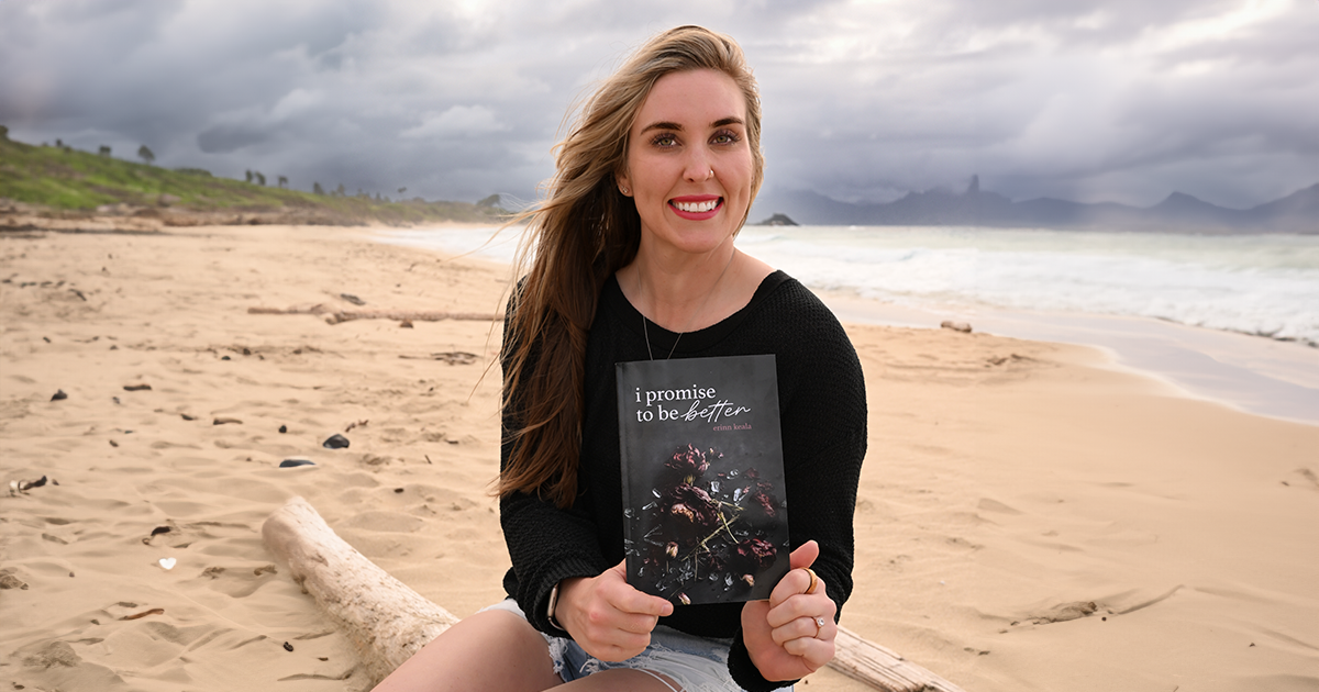 Erinn Keala holding a copy of her book on the beach. 