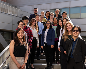 magnify-363-241 Group including undergrad students stand on steps in front of building