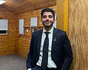 Alharthi-363-241 Mohammed Alharthi in suit and tie standing inside a wood-paneled room