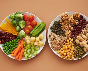 food+plate-363-241 Two plates display vegetables and halved tomatoes, nuts and legumes including chickpeas and walnuts