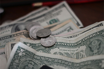 A few coins on top of several one dollar bills