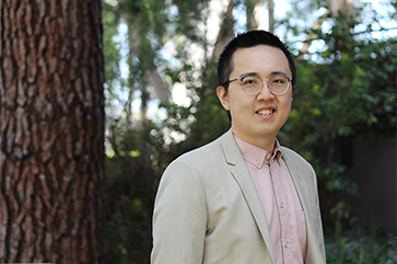Eric Min outdoors in peach button-down and beige jacket