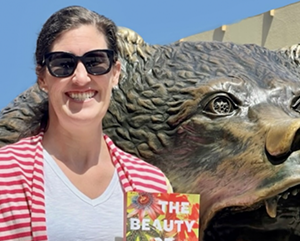 Lauren-Stienstra 363 – 241 Lauren Stienstra posing with her book, "The Beauty of The End," with the Bruin Bear Statue in the background.