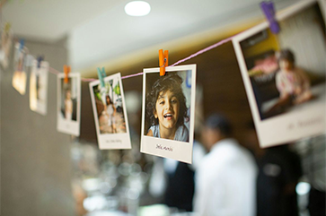 Polaroid photos on a string. Most of the images are blurry, but the clear one is the head of a smiling child.