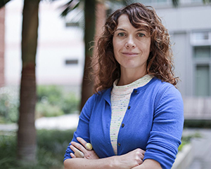 A head-and-shoulders photo of Amy Rowat in a blue cardigan with arms crossed.
