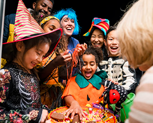 Halloween-363-241 Children in costumes gathered around a bowl of candy.