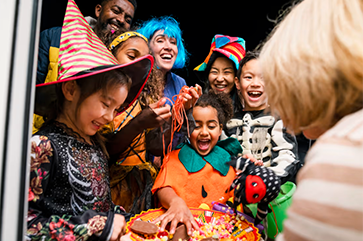 Children in costumes gathered around a bowl of candy.
