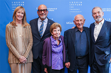 Five smiling people standing in front of Luskin Lecture for Thought Leadership step-and-repeat banner