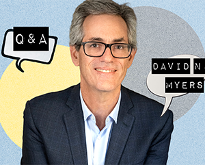 MeetingMinds_DavidMeyersQA_363-241 David N. Myers smiling as he wears a dark checkered suit jacket over a light blue shirt. Behind him is a textured background with overlapping circular shapes in blue, yellow, and gray. Two speech bubbles appear: one on the left reads “Q & A,” and one on the right reads “DAVID N. MYERS.”