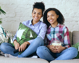 Two teens watch TV and eat popcorn