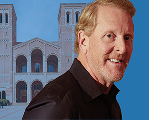 UE_NewsroomBarryEggers_2-363-241 Barry Eggers in front of UCLA’s Royce Hall. The iconic twin-towered building features Romanesque architecture with arched windows and decorative brickwork. The right side of the background is replaced with a solid blue color, creating visual contrast.