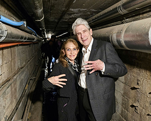 From left: Felicia Knaul, in black-and-white pinstripe suit, and Julio Frenk, in gray jacket and white button-down, making the “fours up” hand gesture