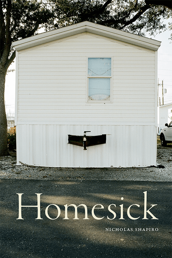 A white mobile home with a small window and an air conditioner is pictured under a large tree. The book title Homesick and author Nicholas Shapiro are written at the bottom.