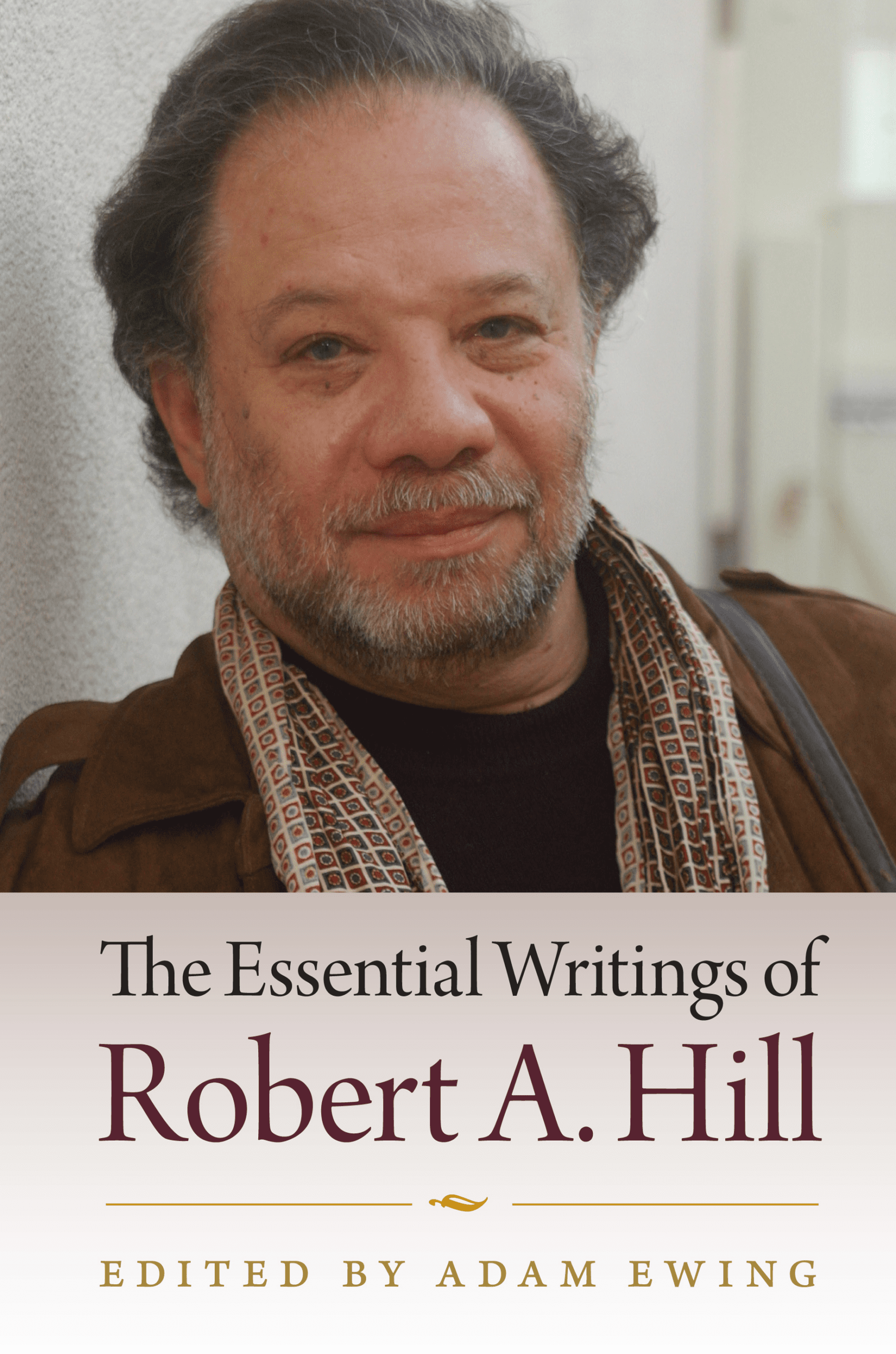 A book cover featuring a portrait of a bearded man in a brown jacket and patterned scarf. The title reads The Essential Writings of Robert A. Hill, edited by Adam Ewing.