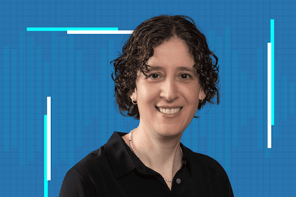 A person with short, curly brown hair and a pearl necklace smiles at the camera, wearing a black shirt. The background features a blue grid with white and light blue bar graphics.