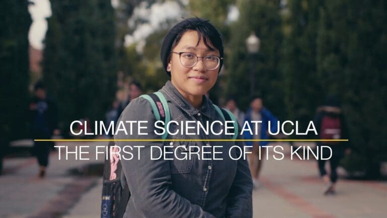 A person with glasses and a beanie stands outdoors on a campus path, wearing a backpack. Text over the image reads: CLIMATE SCIENCE AT UCLA: THE FIRST DEGREE OF ITS KIND. Trees and people are in the background.
