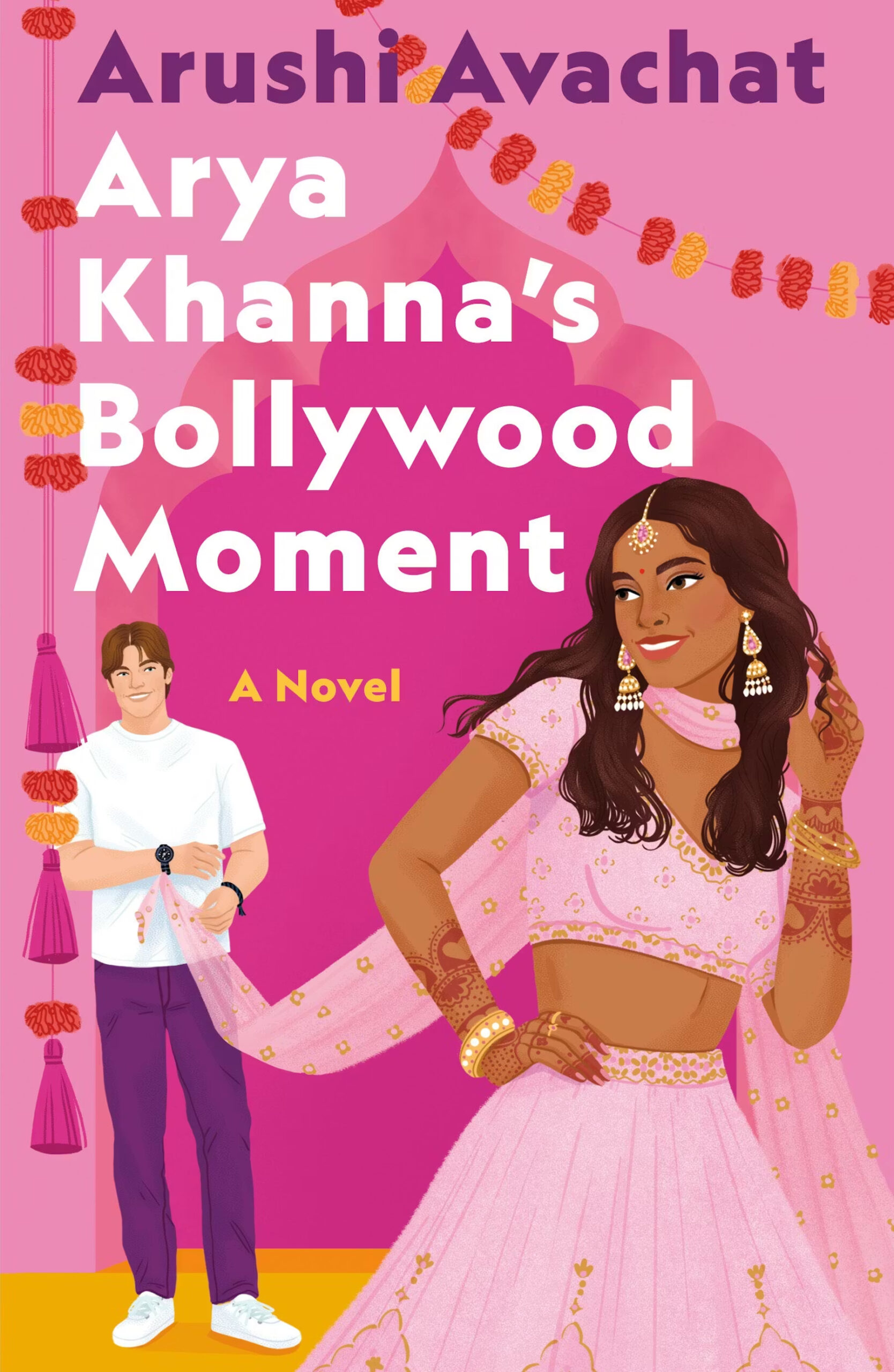 Book cover of Arya Khannas Bollywood Moment by Arushi Avachat, featuring a woman in a pink lehenga dancing, with a man in casual clothes in the background, and festive decorations above them.
