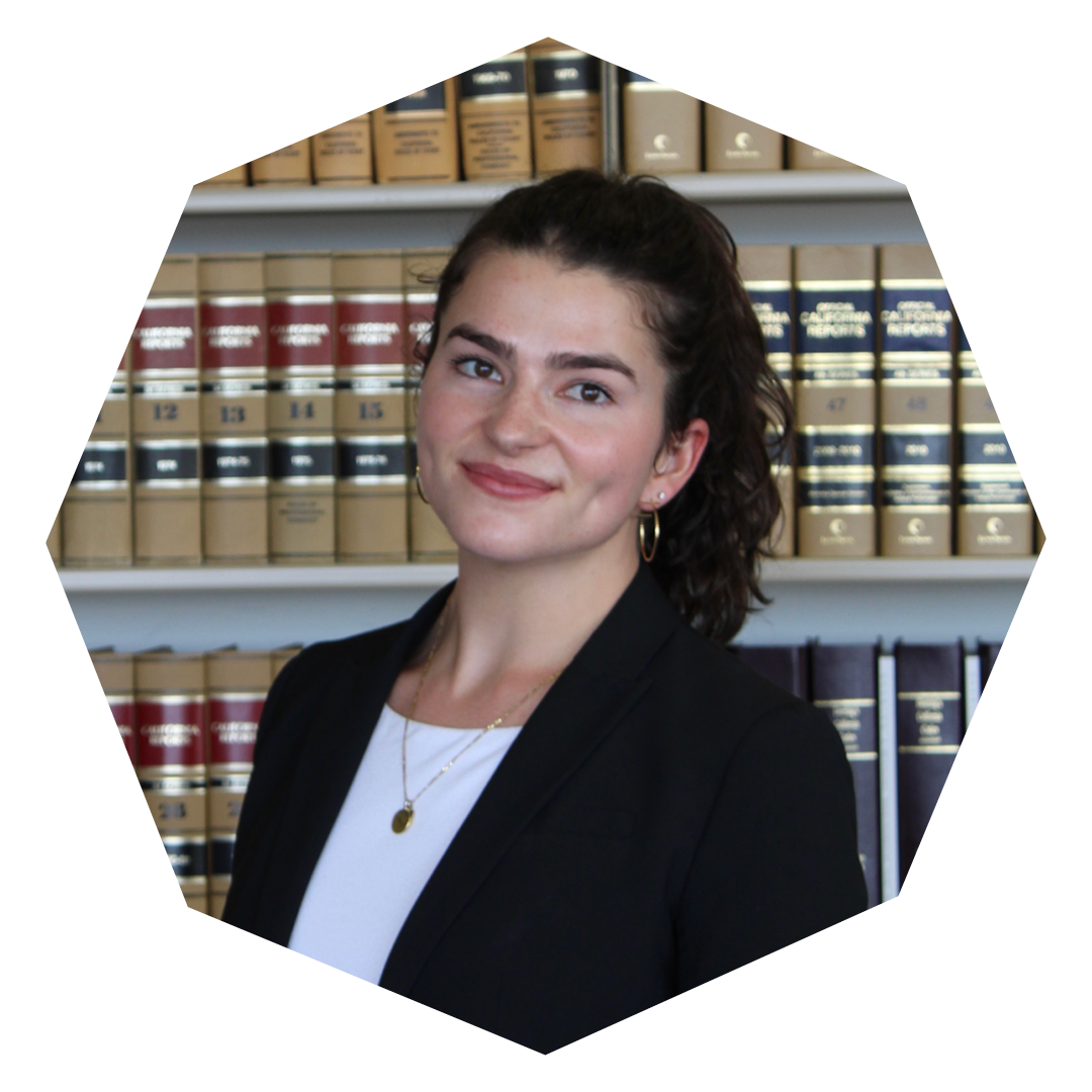 A woman in a black jacket and white shirt with dark hair standing in front of shelves of legal books