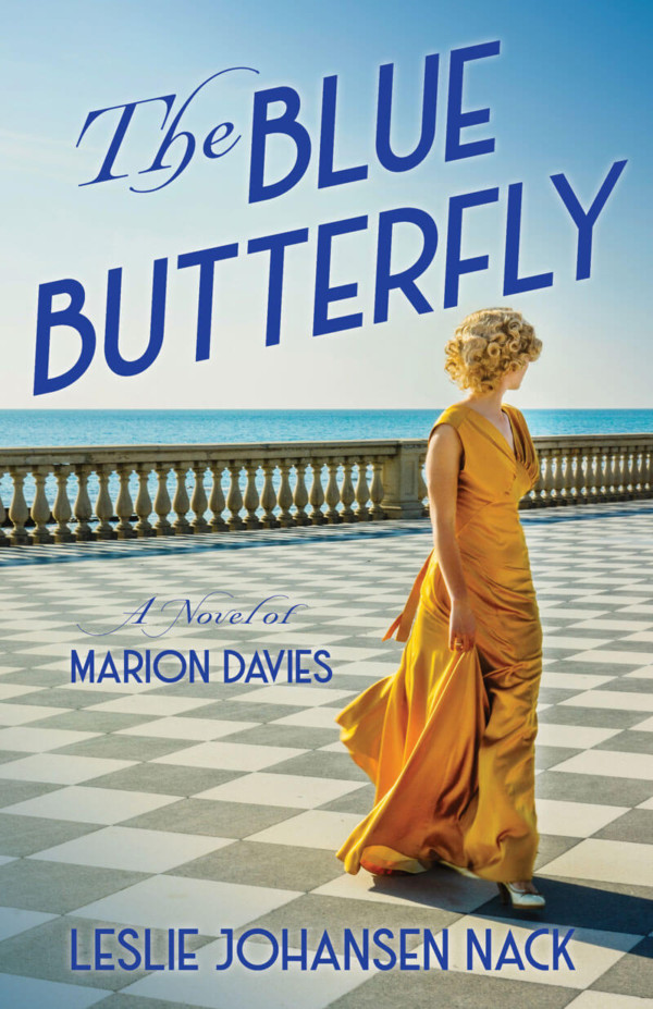 book cover of The Blue Butterfly featuring a woman walking on tiles by the sea